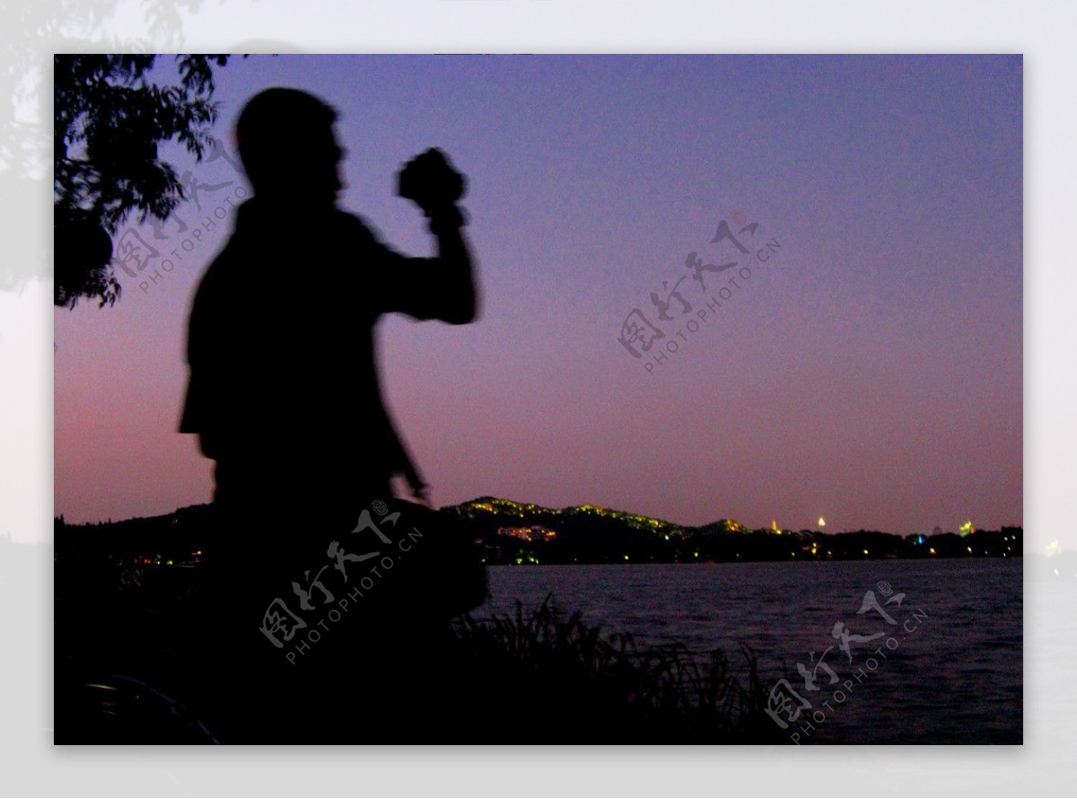 西湖边黄昏中的摄影者图片