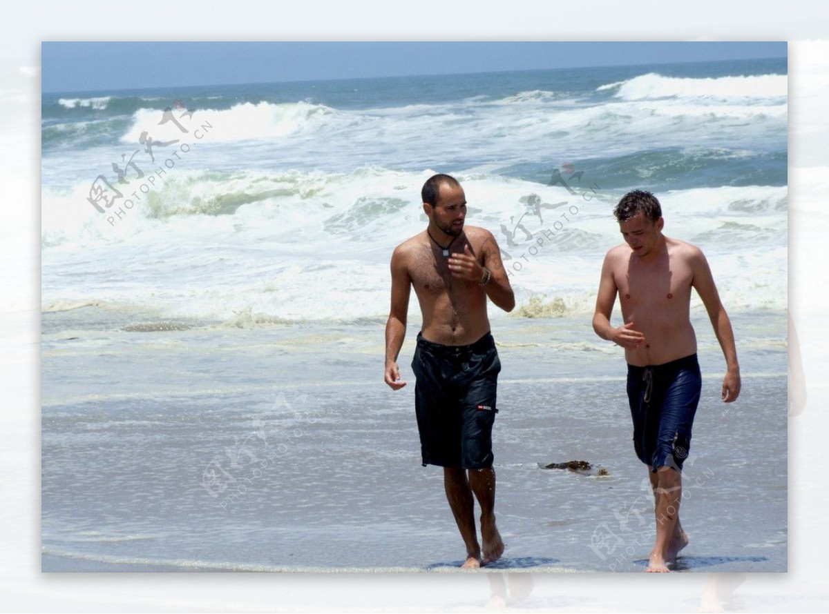 热带海边浪花两男人士沙滩踩浪图片
