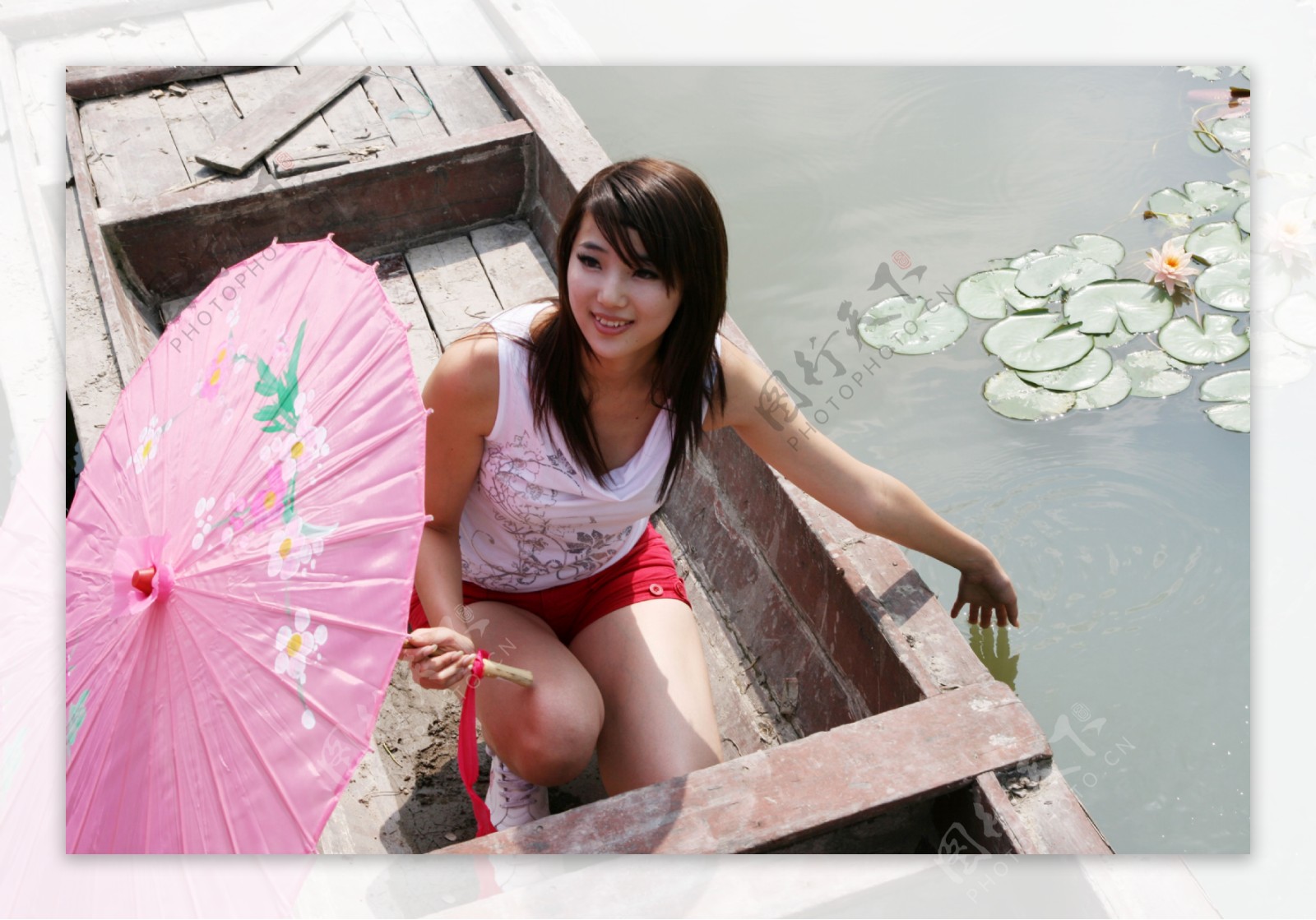 小木船上戴着伞的美女图片