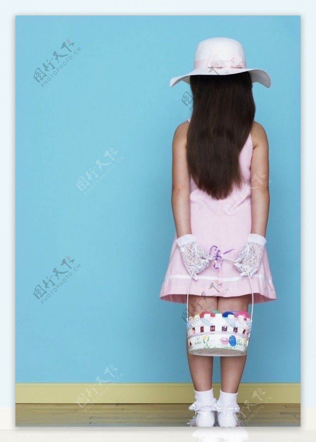 面对墙站着背手拿着小篮子的小女孩图片