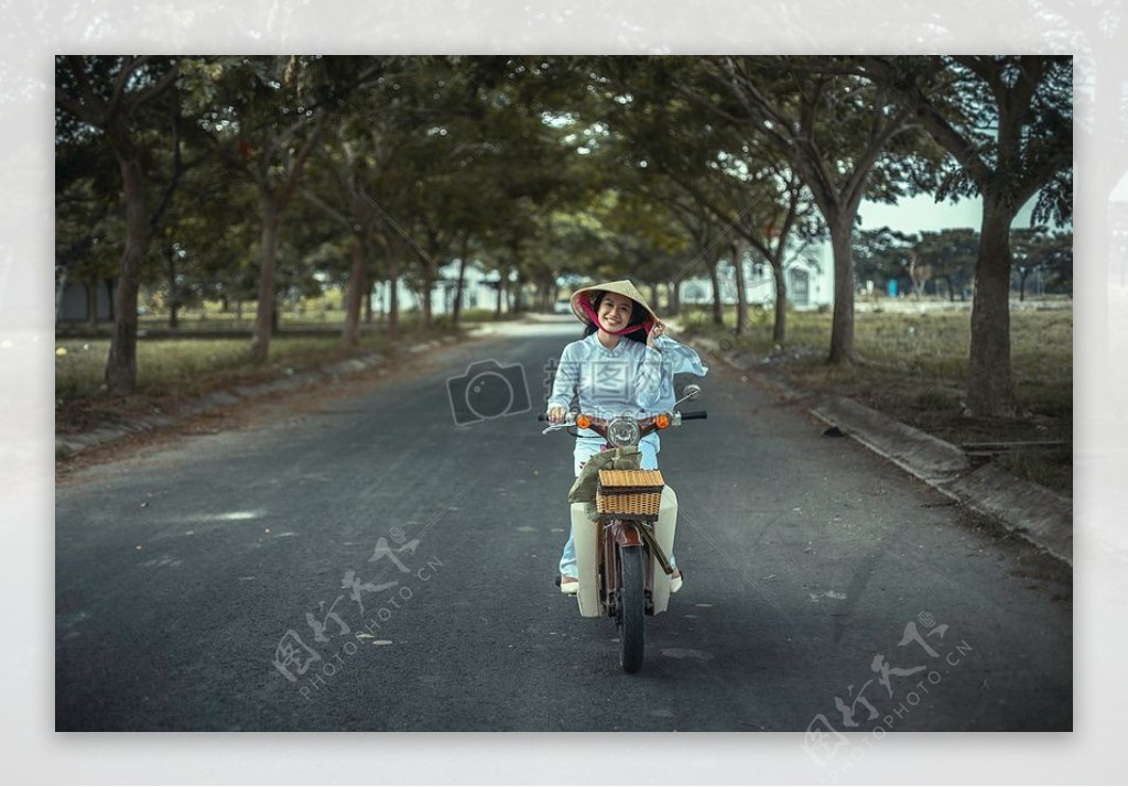 女人微笑而白天在公路附近的树木骑自行车