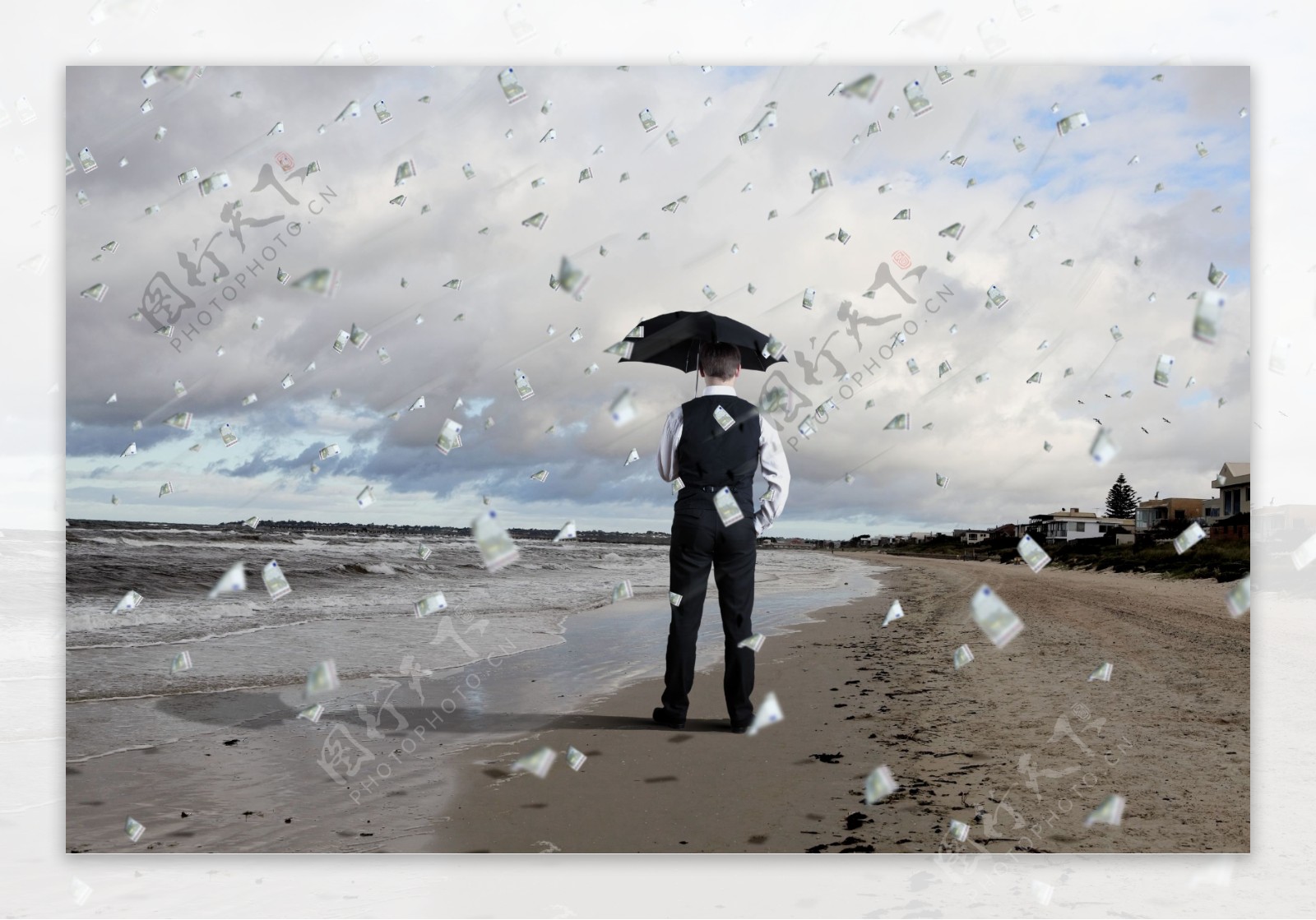 海边打伞的男人和钞票雨图片