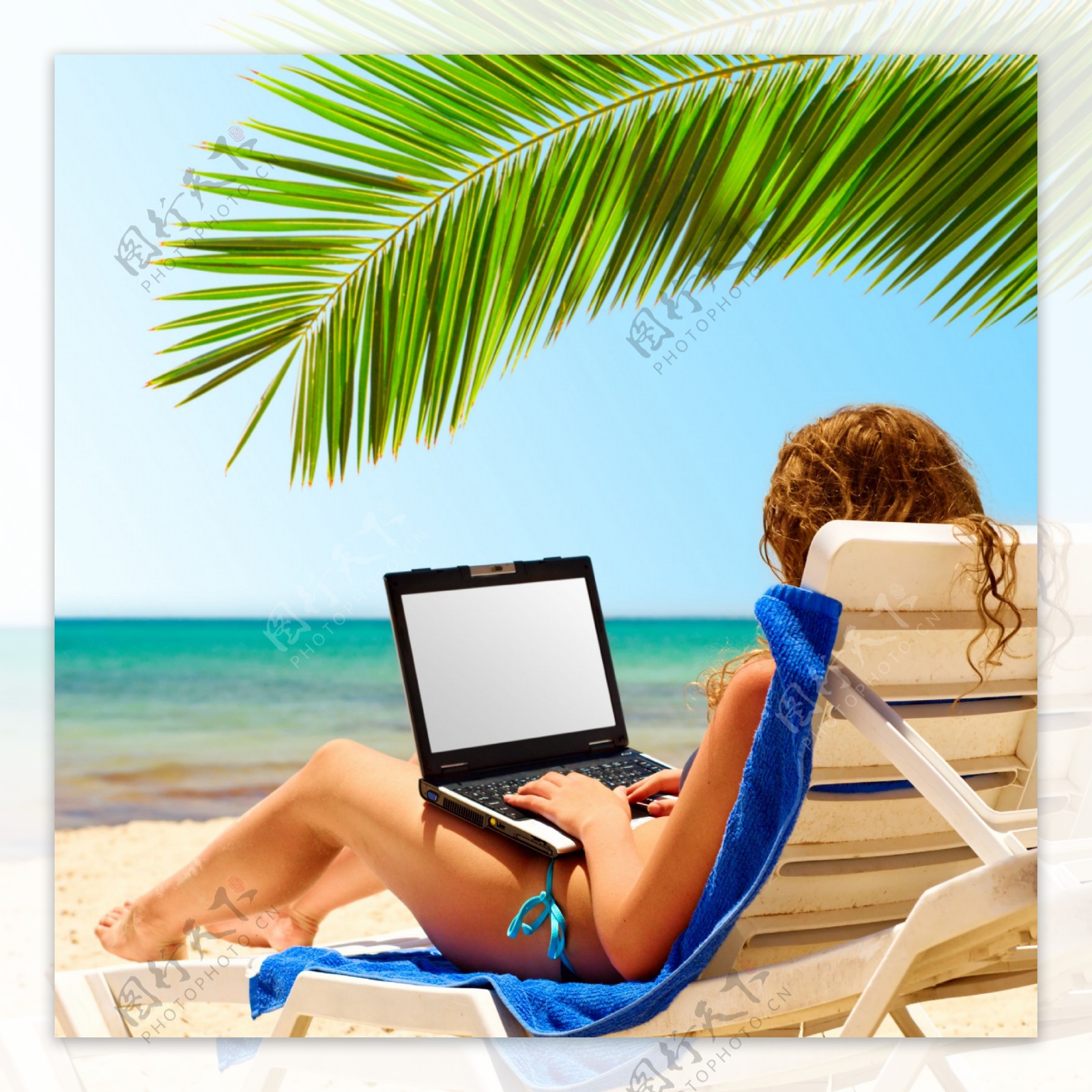 海边坐躺椅上玩电脑的美女图片