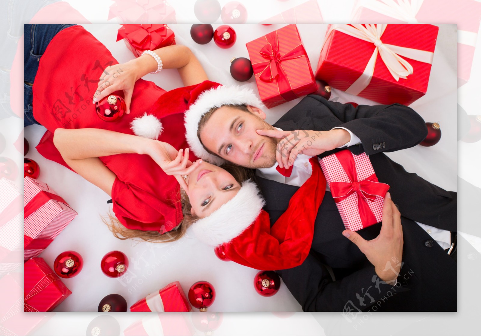 躺在礼物和圣诞吊球中的男女图片