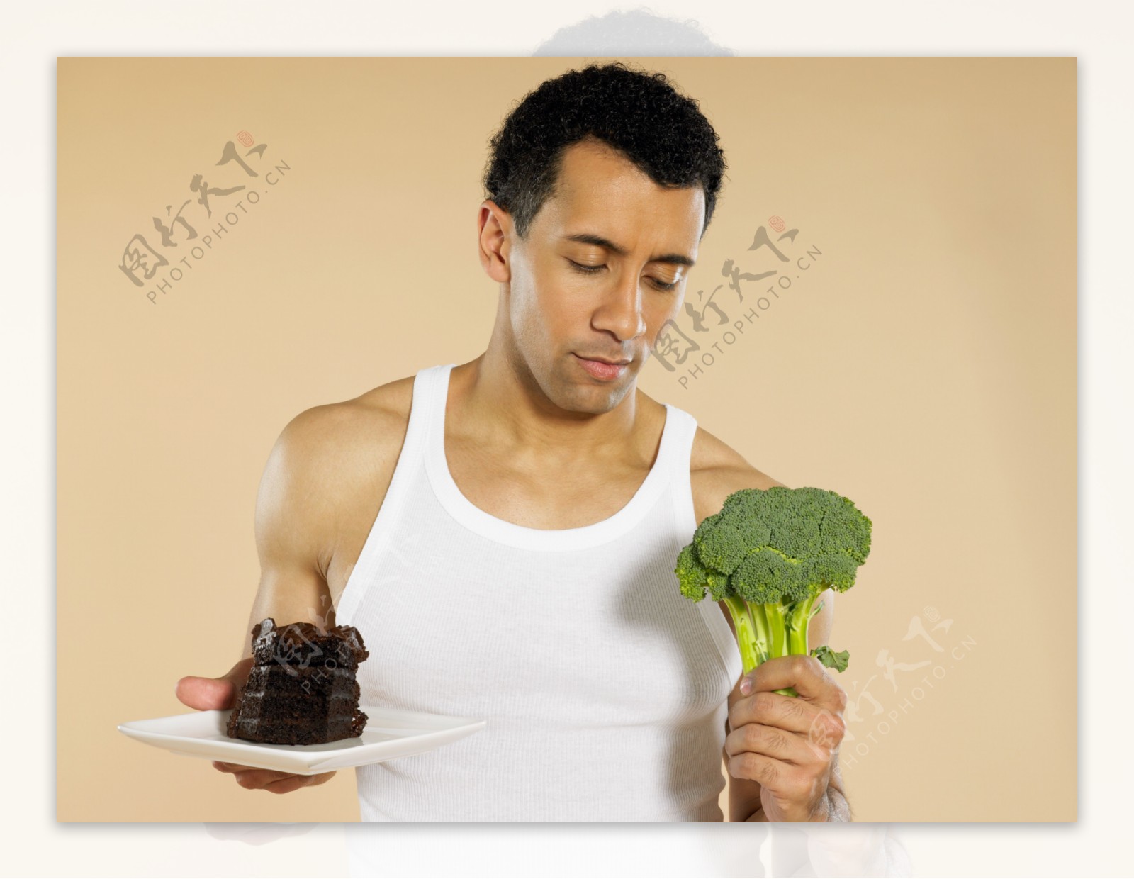 手拿巧克力蛋糕和蔬菜的外国男性图片