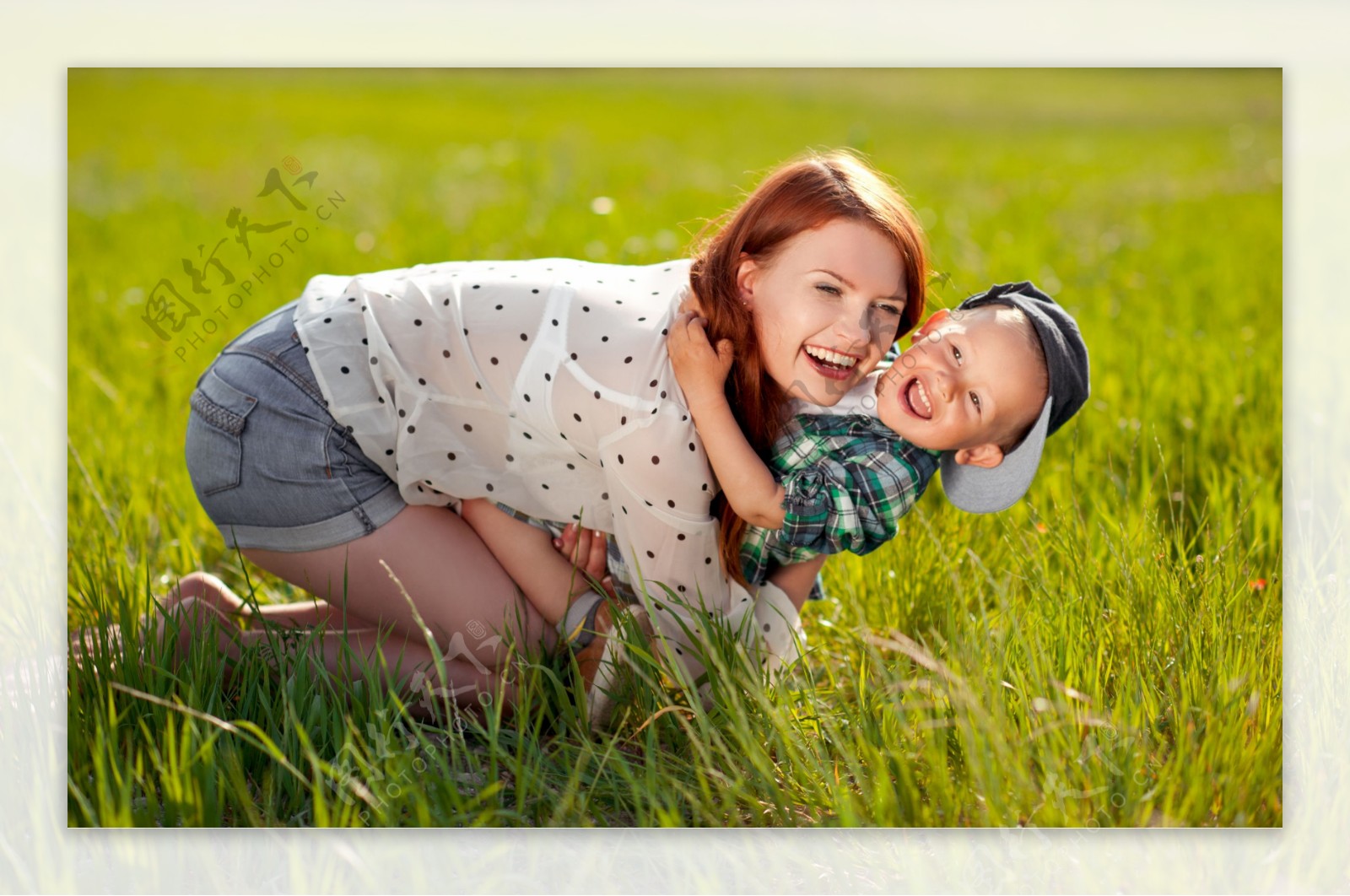 草地上抱着孩子玩耍的女人图片
