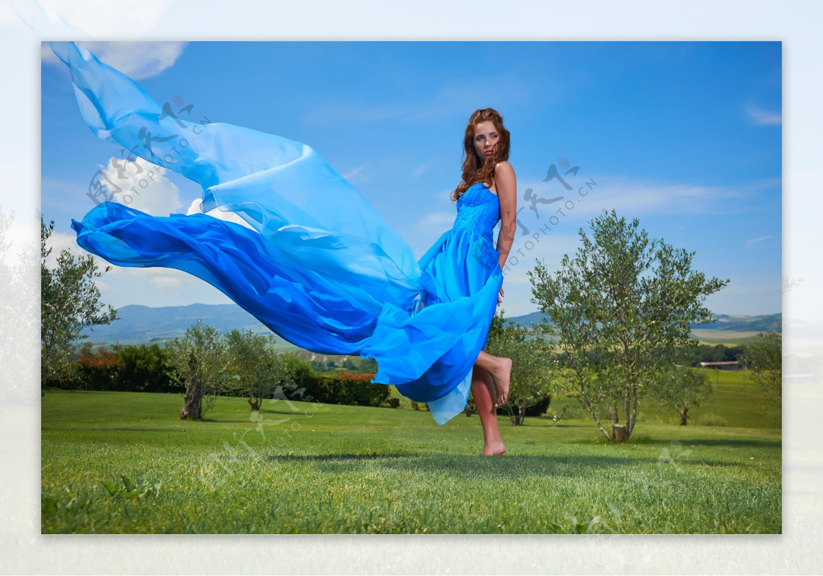 草地上舞动蓝裙的美女图片