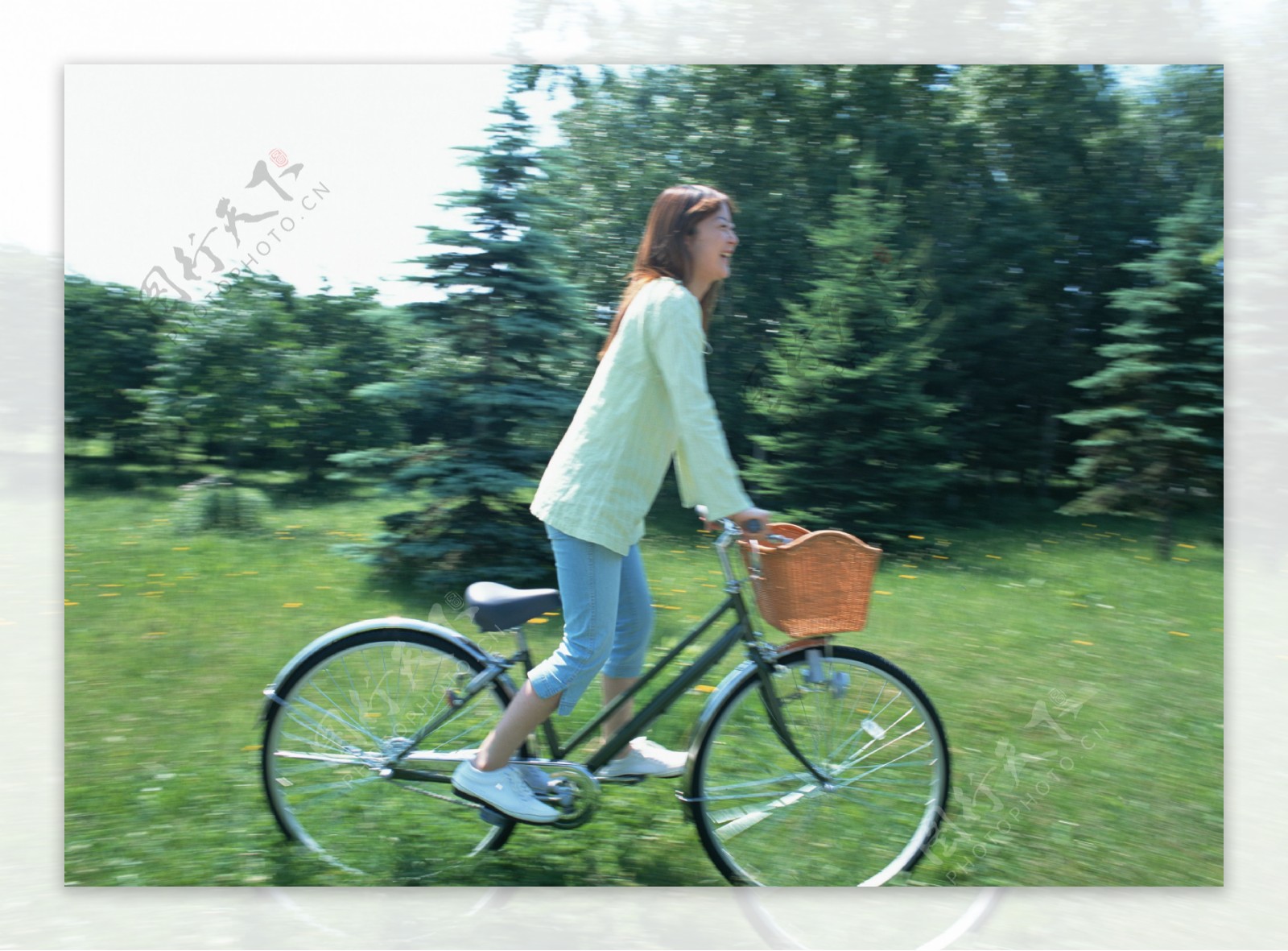 草地上开心骑自行车的美女图片