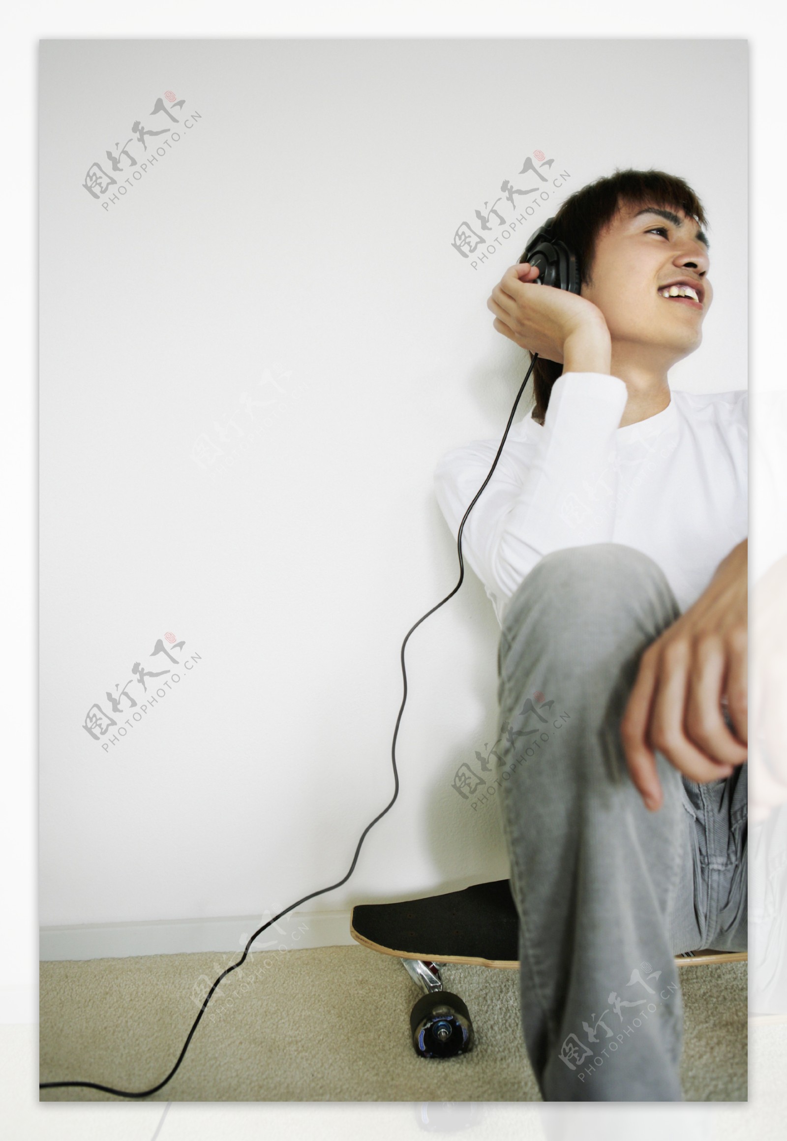 坐在滑板上听音乐的男生图片
