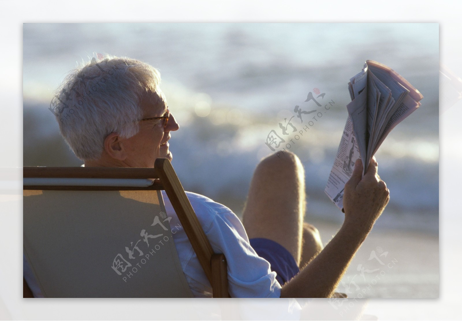 海滩上看报的老人图片