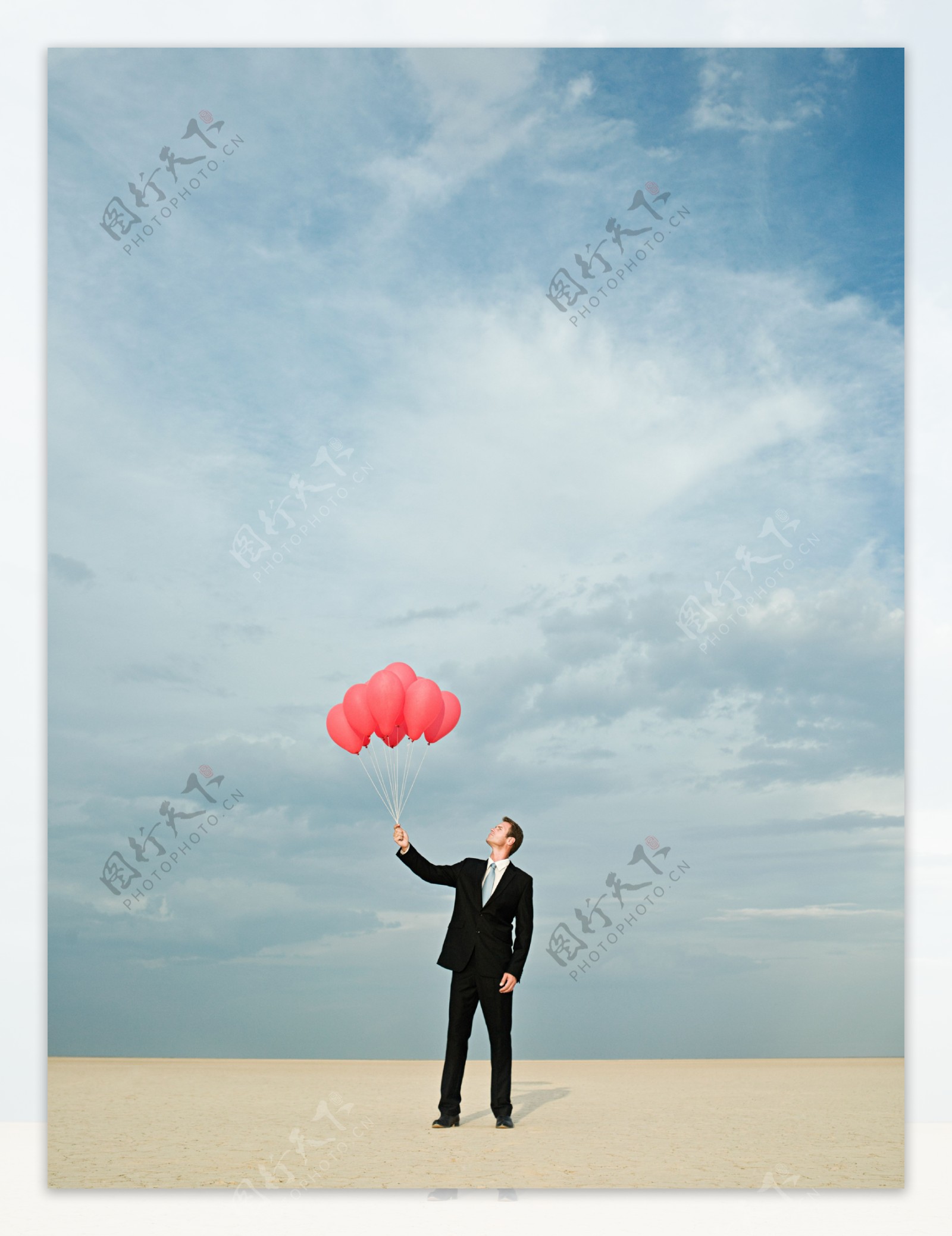 蓝天下拿着一把红气球的外国男人图片